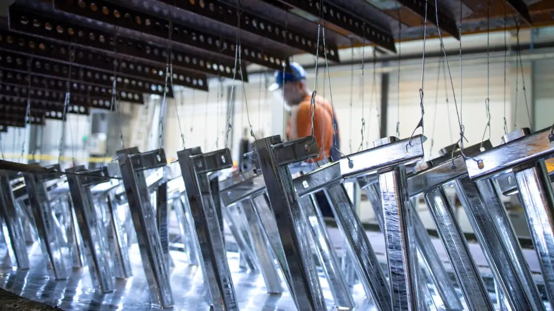 Perfiles de acero colgados en racks en una línea de recubrimiento galvánico, clave para saber cómo elegir un recubrimiento metálico industrial